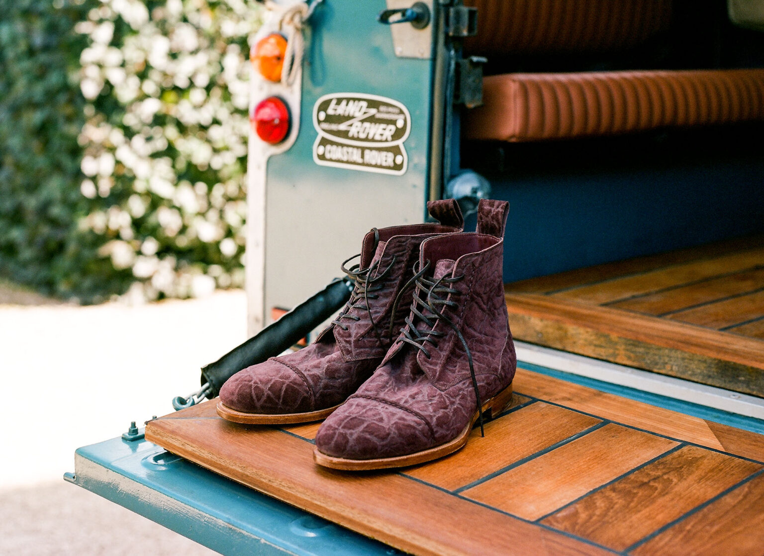 A pair of Barrack 'Stanley' WWII Boot in Dark Tobacco CF Stead Janus Calf with Edwin emboss resting on the rear tailgate of a vintage Land Rover Defender