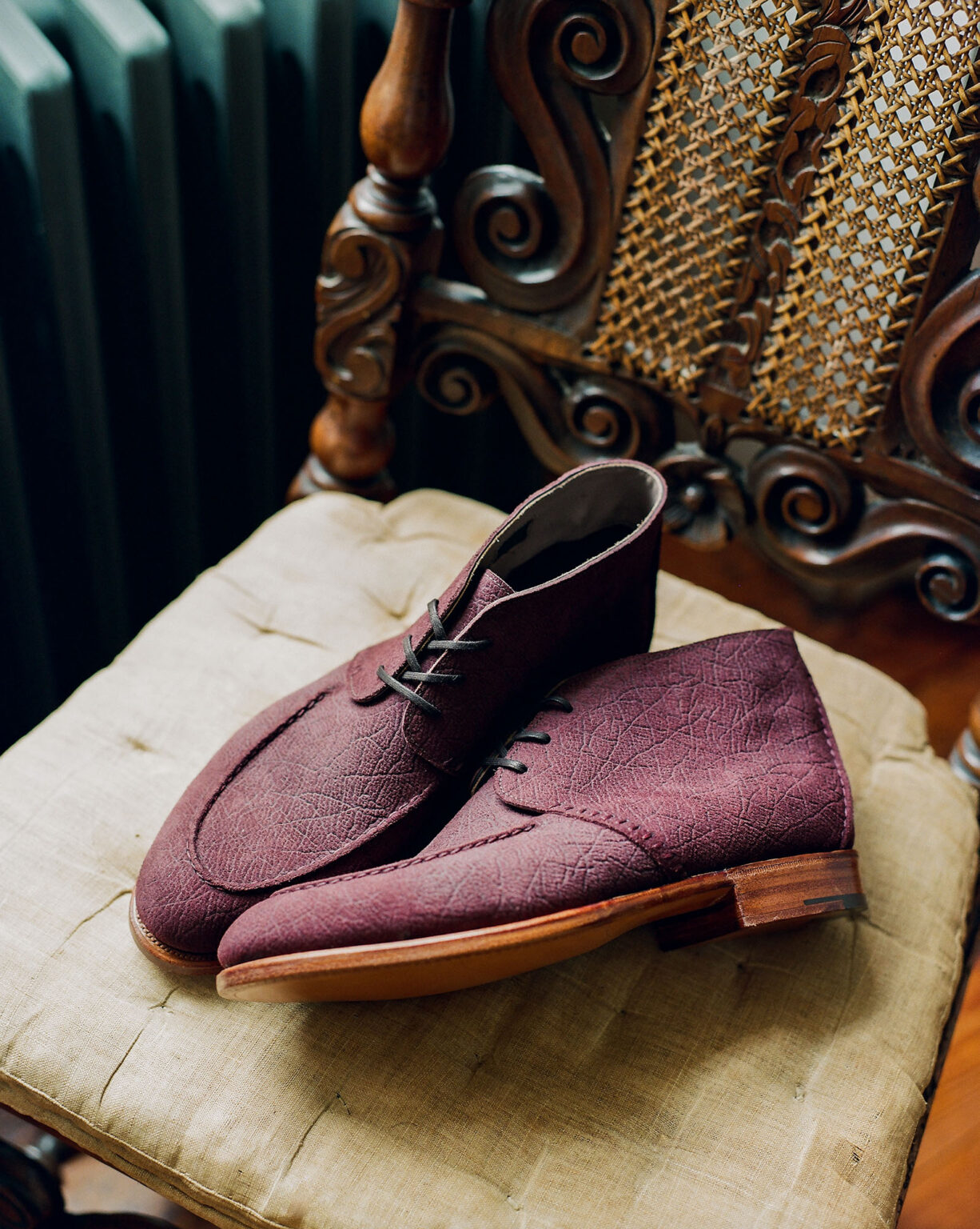 A pair of E.Woodford Edgware Ankle Boots in Dark Tobacco CF Stead Janus Calf leather resting on a vintage chair