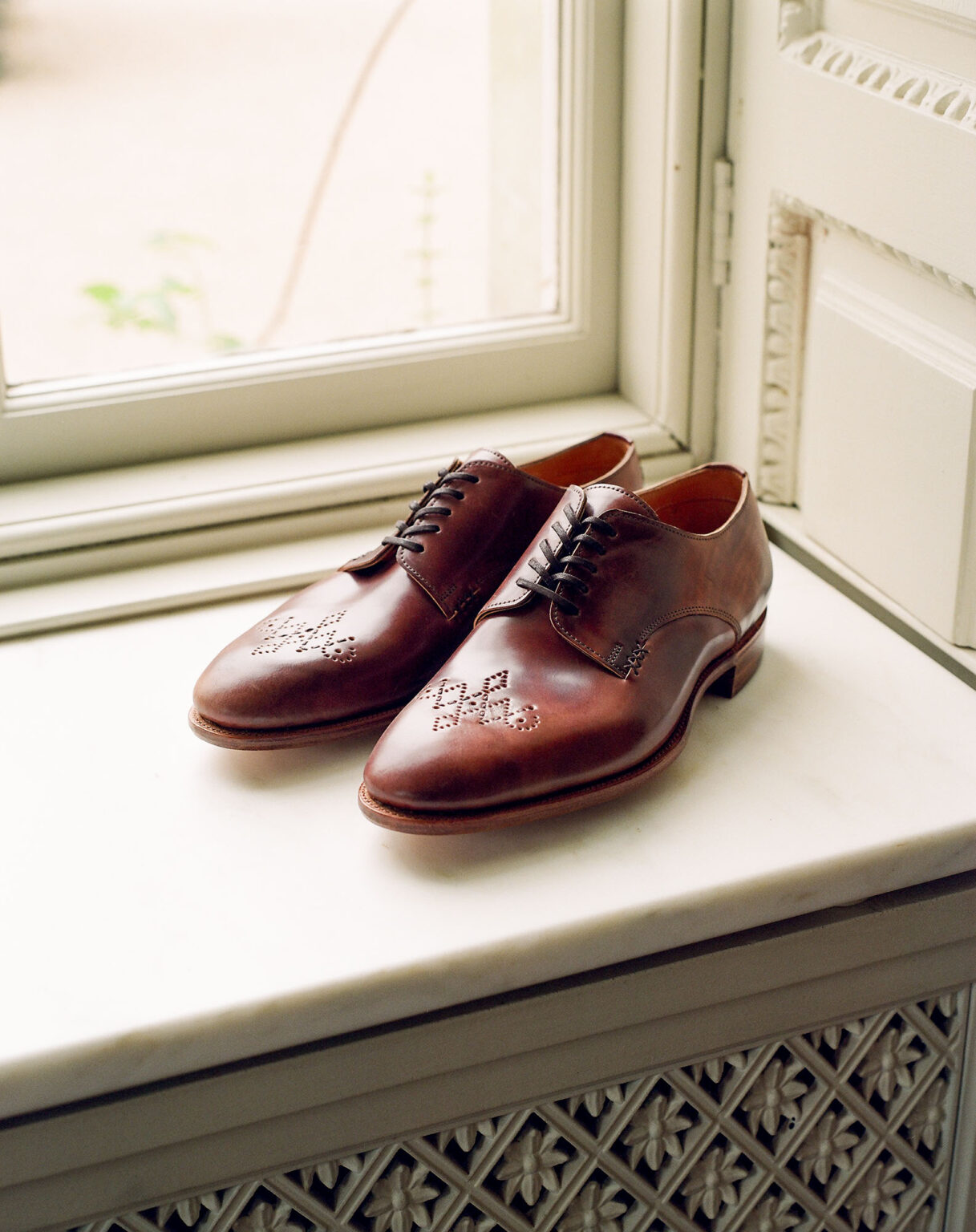 A pair of E.Woodford Kennington Gibsons in No.8 Marbled Horween Shell Cordovan sitting in a bay window sill with morning late flooding in