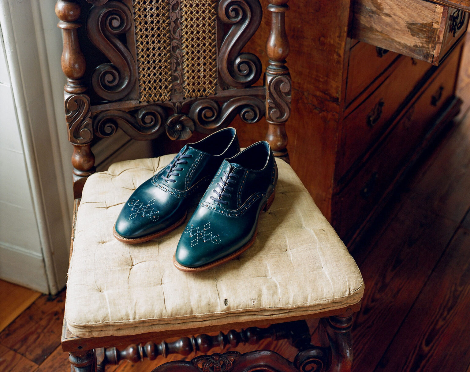 A pair of E.Woodford Redbourne Five Eyelet Oxfords in Navy Horween Shell Cordovan leather sitting on a vintage ornate chair