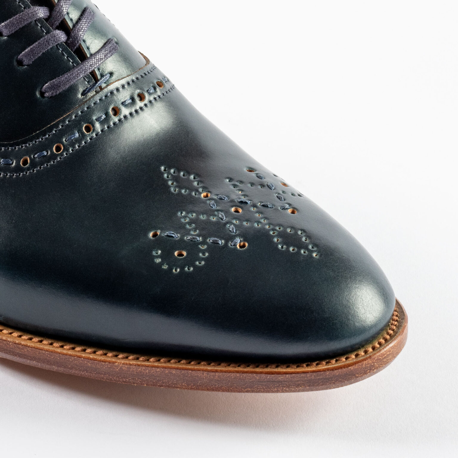 Closeup of signature E.Woodford medallion on Redbourne Oxford in Navy Horween Shell Cordovan