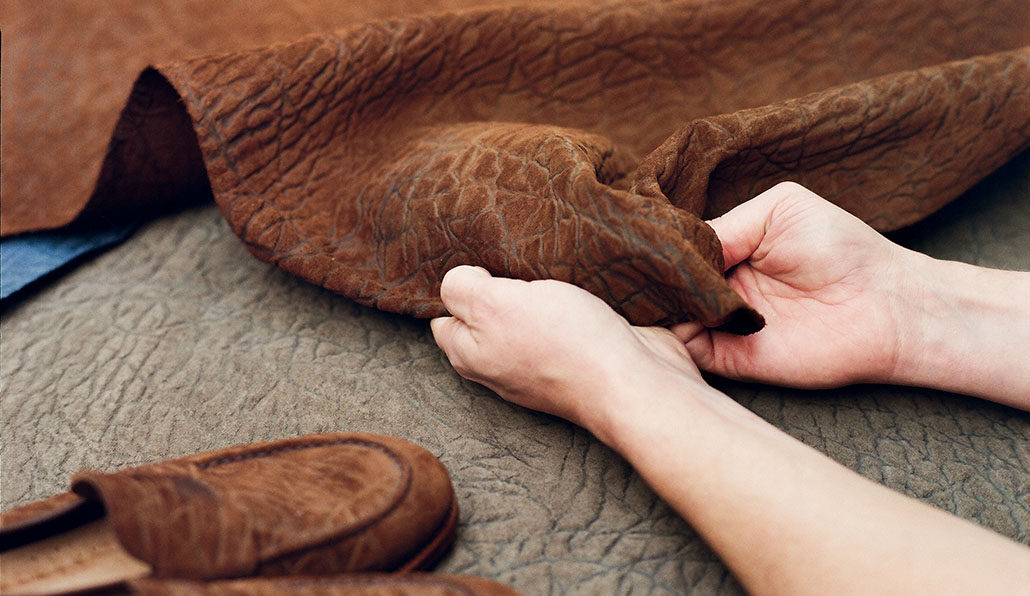 CF Stead Janus Calf Suede material with Edwin Emboss in Dark Chestnut and Fog colours being inspected in the E.Woodford factory with a pair of Watling loafers in the foreground